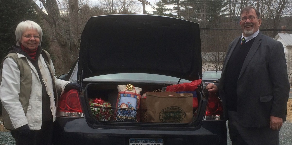 Man and woman standing at car trunk full of gifts