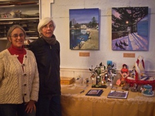 Woman artist with friend standing in front of art display