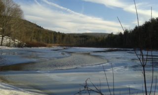 Partially open water with ice surround and hills in the distance
